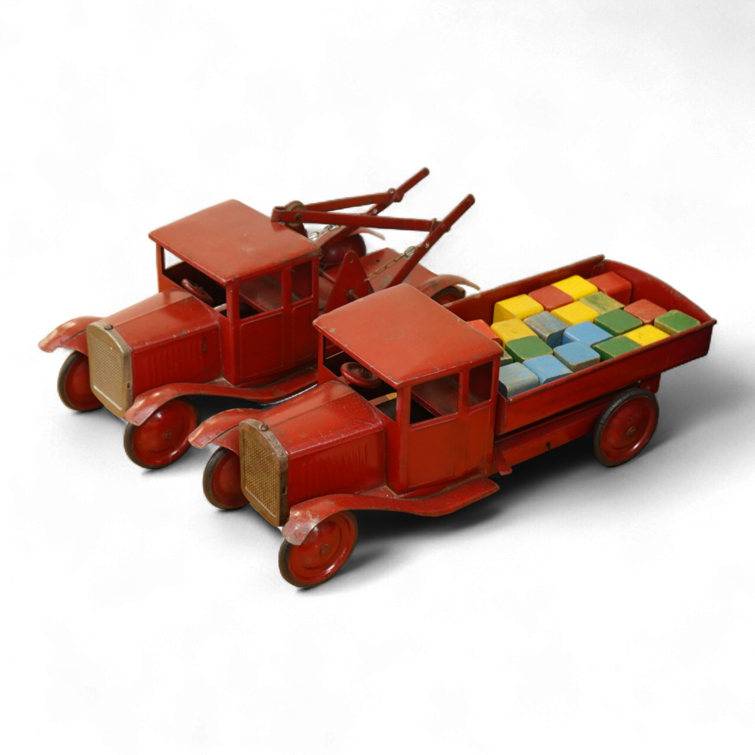 Two 1930's/40's Tri-ang large scale tinplate trucks, both with similar frames and cabs, one as a wreck truck with mounted crane, the other has a wagon with painted wooden blocks, each approximate 44cm long